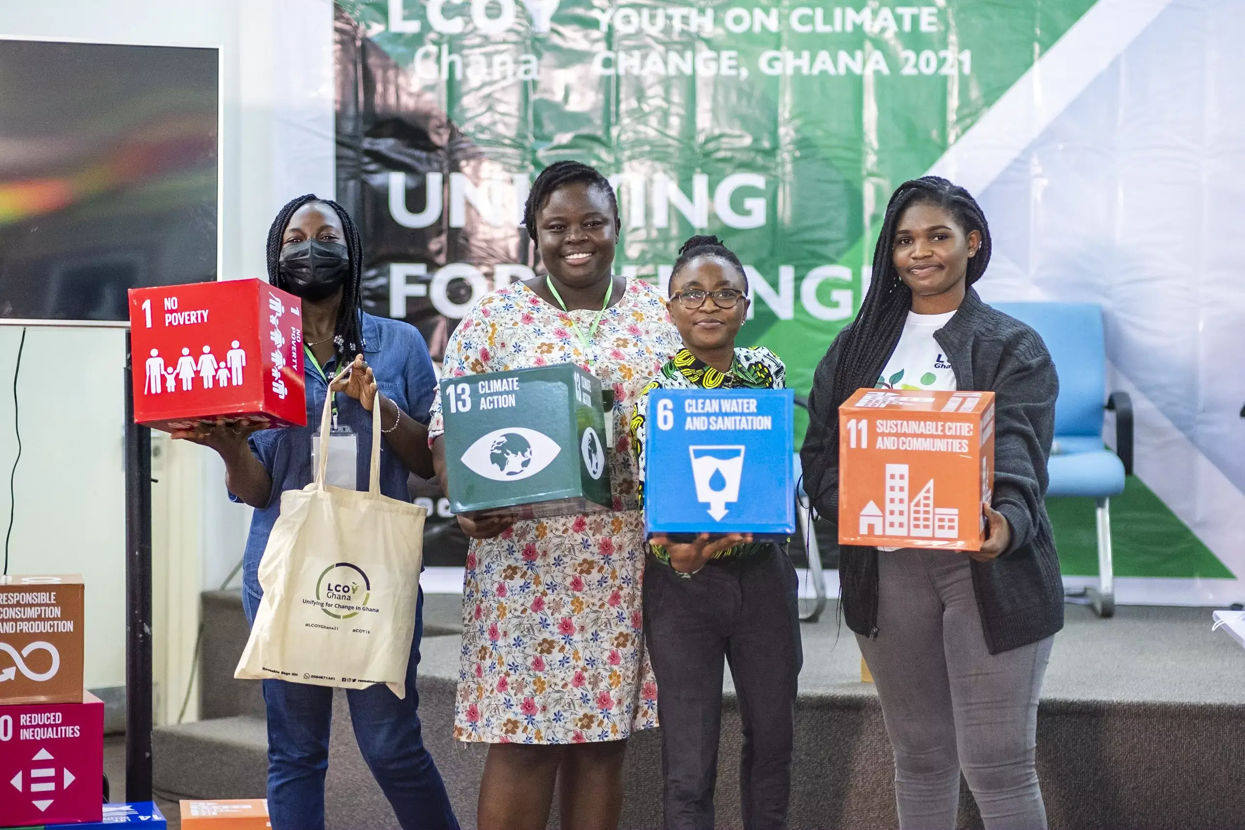Women holding boxes about climate action, no poverty, clean water and sanitation, sustainable cities and communities at a uniyia event.